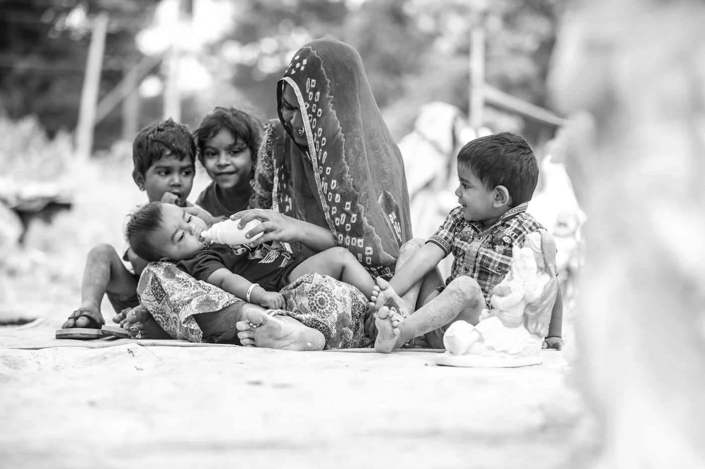 Small children sitting on the ground with their mother on a street in India