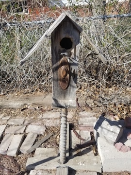 Finished wooden birdhouse with a weathered finish hanging outdoors.