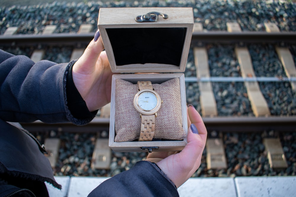 a person is holding a watch in a box
