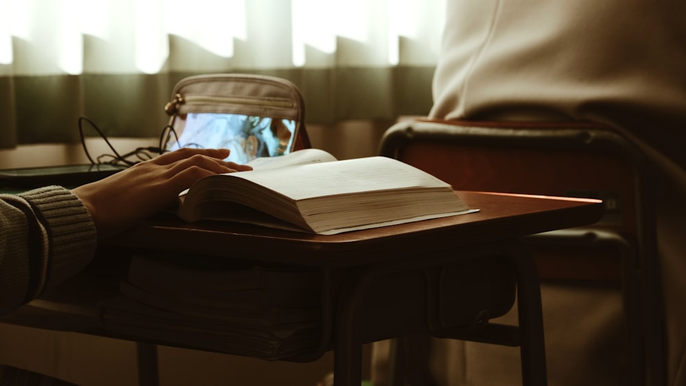 a person sitting at a table with a book and a laptop