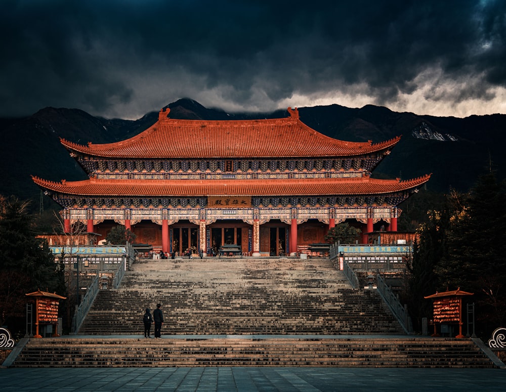 a person standing in front of a building with mountains in the background