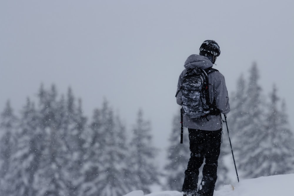 a person with a backpack standing on a snowy hill