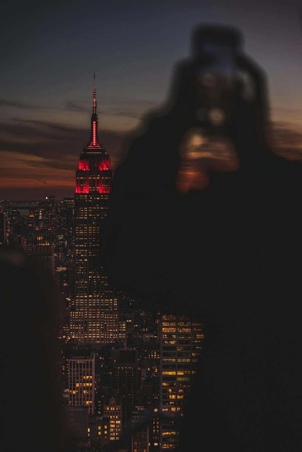 a person taking a picture of the empire building at night