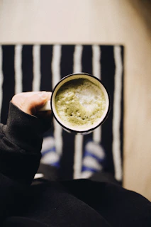 a person holding a cup of green tea