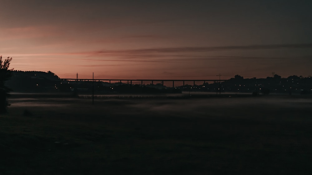 Un campo nebbioso con un ponte in lontananza
