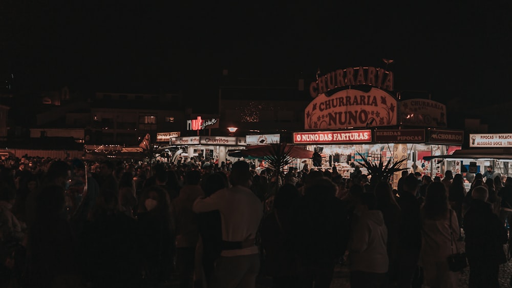 a crowd of people standing in front of a building at night