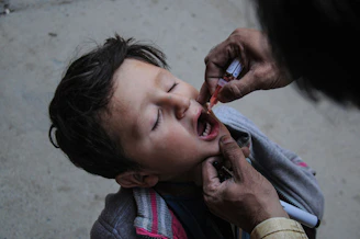 a little boy getting his teeth brushed by an adult
