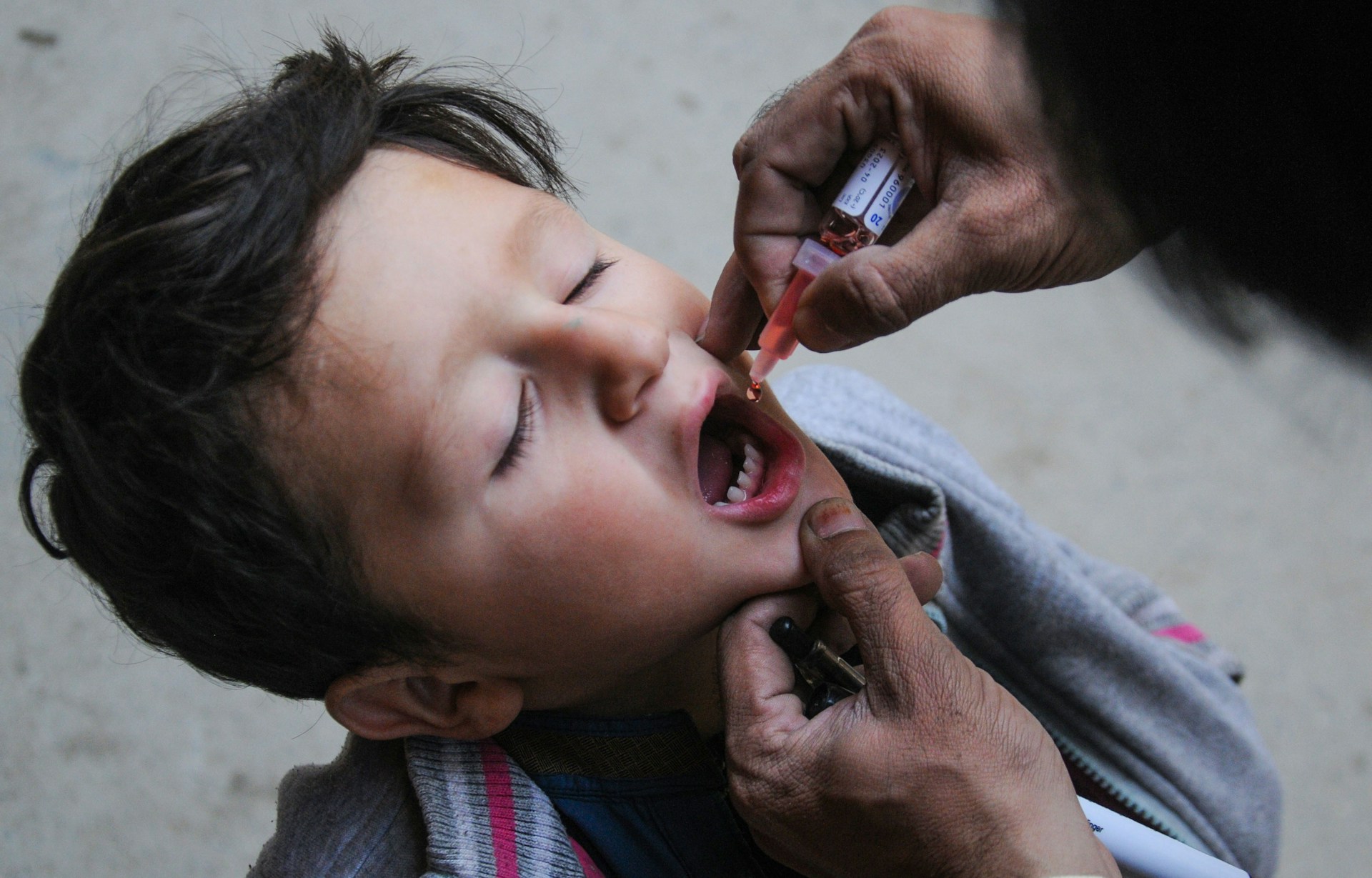 a little boy getting his teeth brushed by an adult