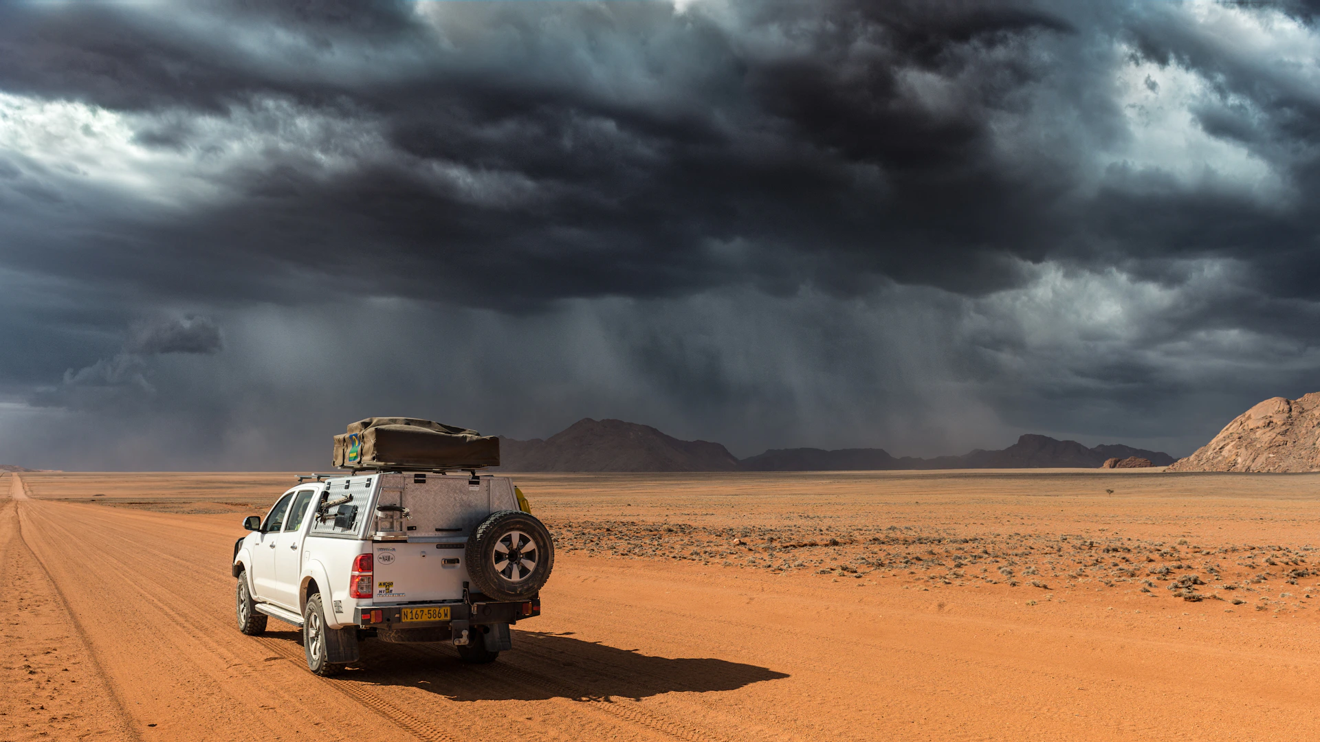 A wide shot of a truck cruising through a vast open landscape under a dramatic sky, embodying the spirit of travel and adventure.