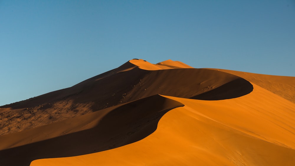 Un gruppo di dune di sabbia con un cielo blu sullo sfondo