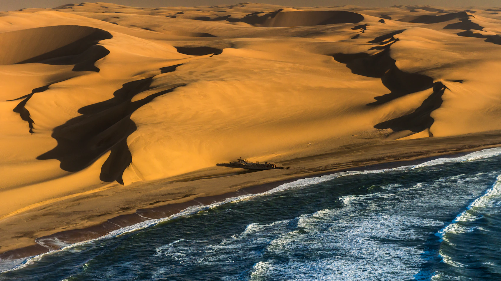 A shipwreck and desert shoreline seen from above on Namibia’s Skeleton Coast