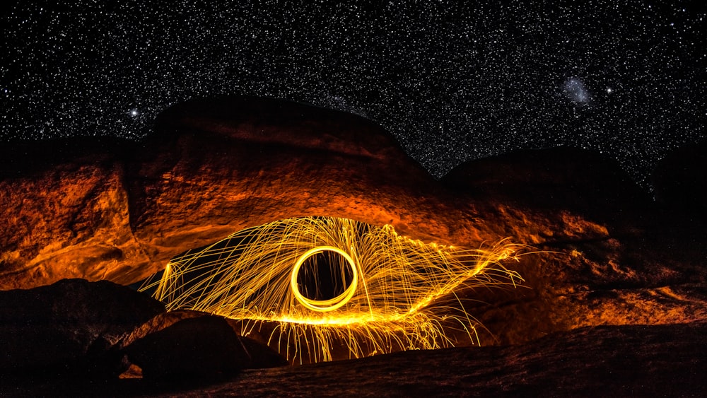 a man standing in front of a large rock with a light painting on it