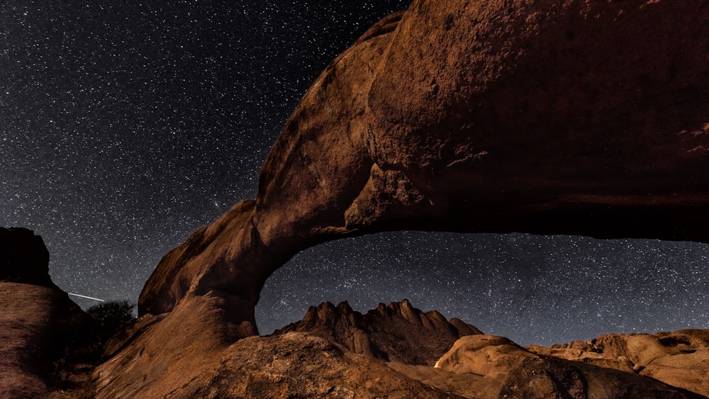 a large rock formation with a sky full of stars in the background