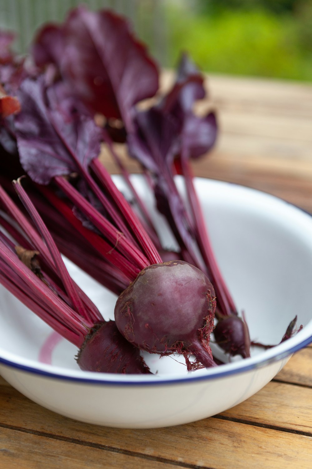 a bowl filled with beets sitting on top of a wooden table