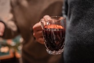 Close-up of a hand pouring deep red wine into a glass inside the cozy tasting room.