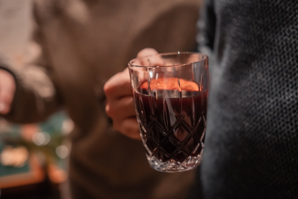 une personne tenant un verre de vin rempli de liquide