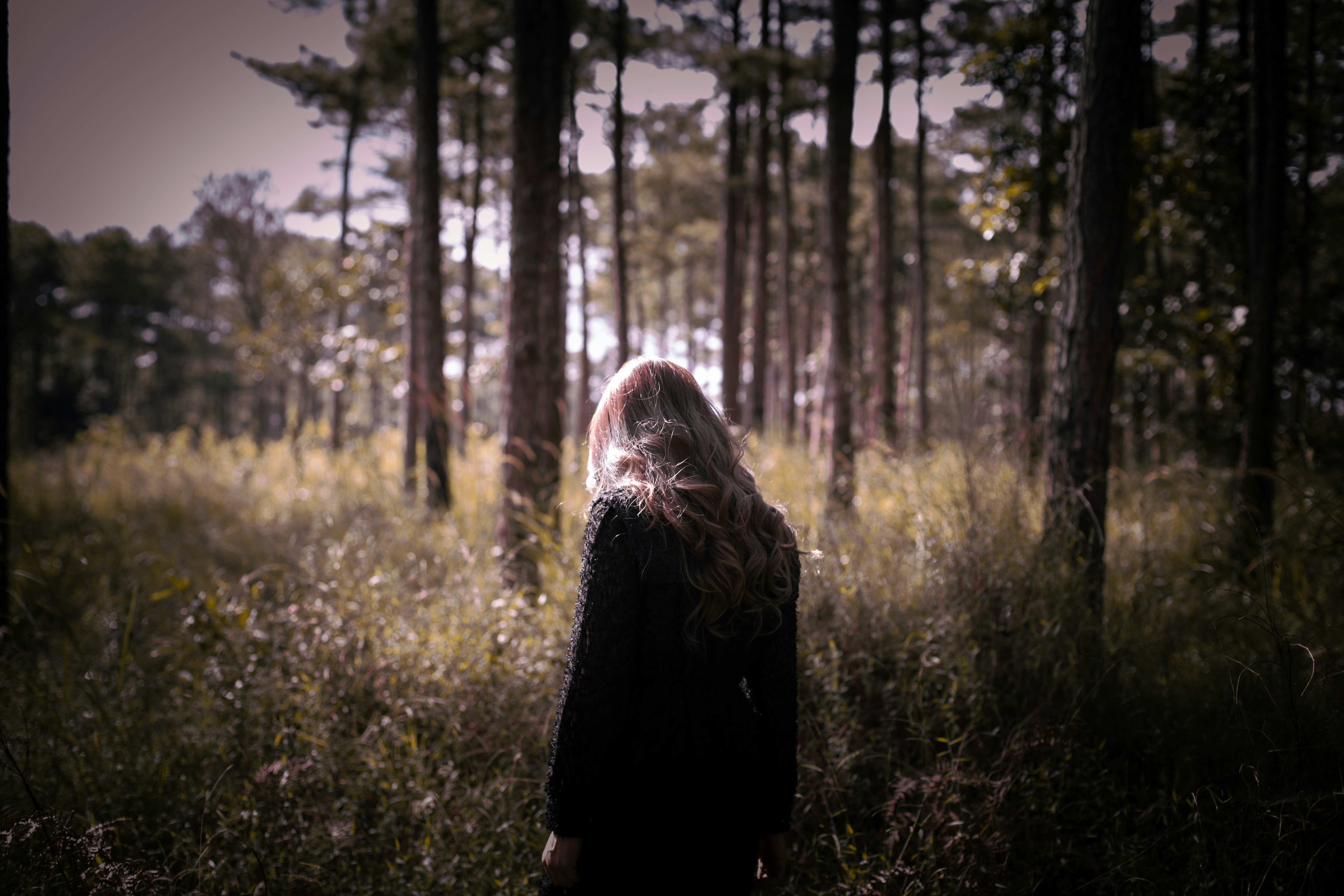a woman standing in the middle of a forest