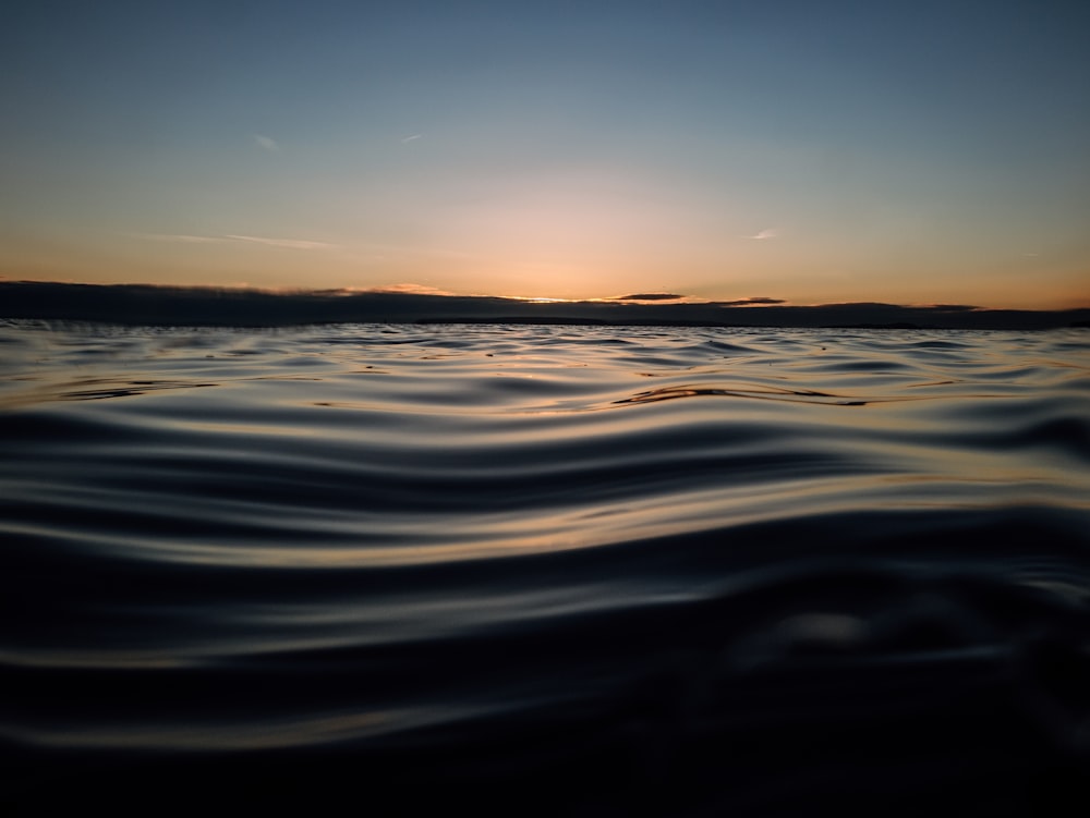 a body of water with a sunset in the background