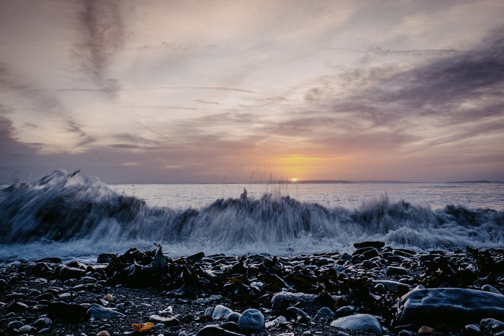 the sun is setting over the ocean as waves crash