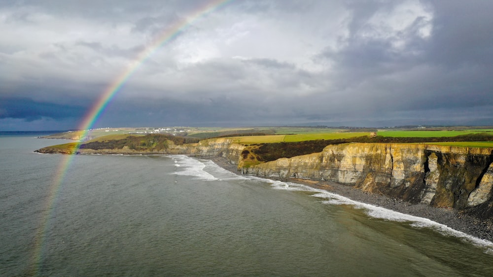 a rainbow shines in the sky over the ocean