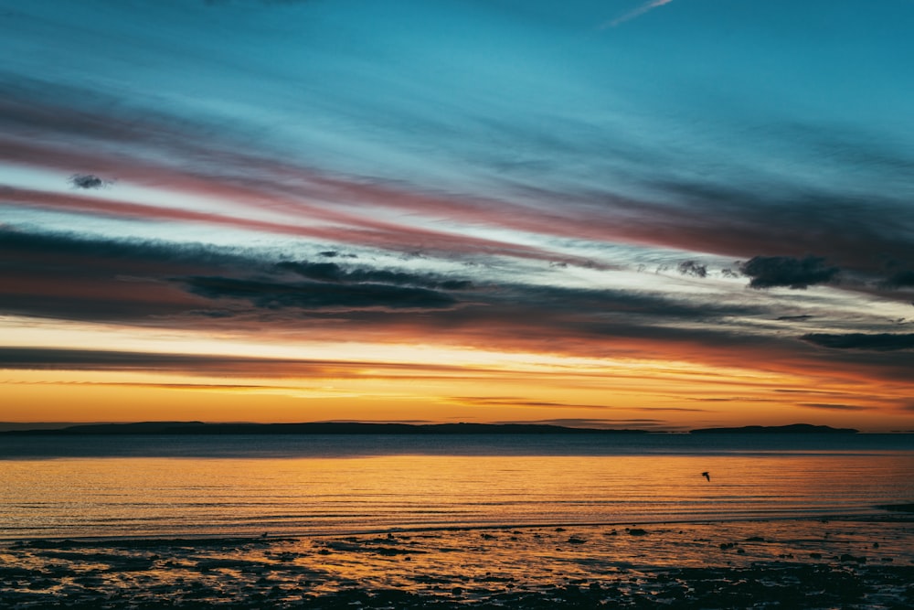 a person walking on a beach at sunset