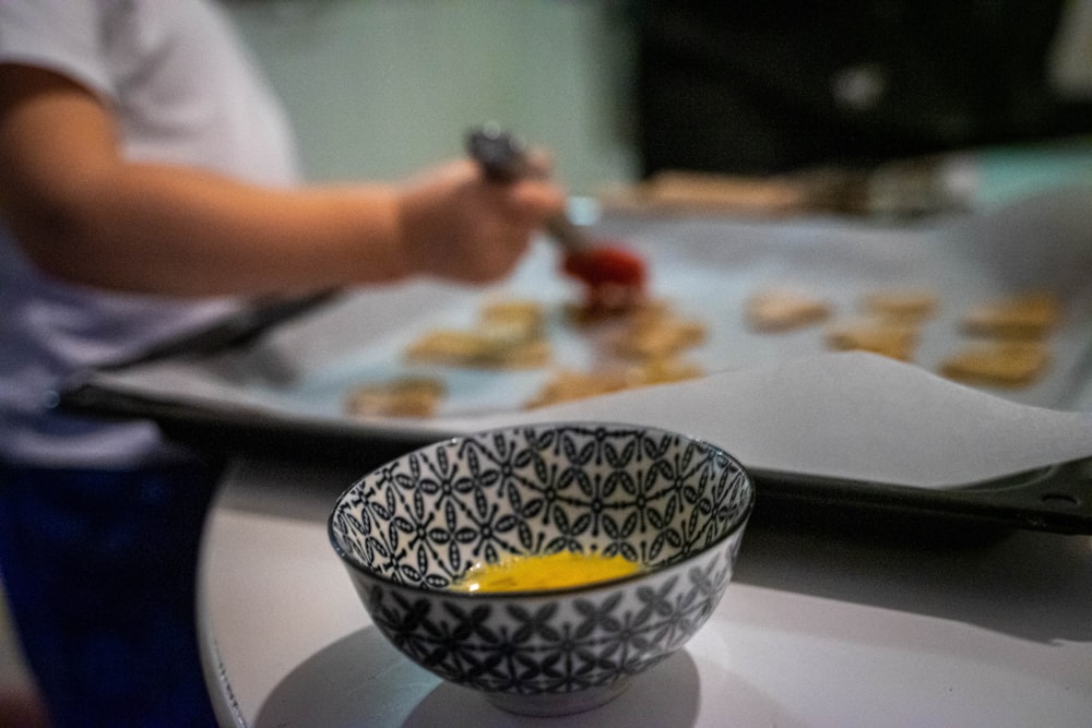 uma tigela de comida em uma mesa com uma pessoa no fundo