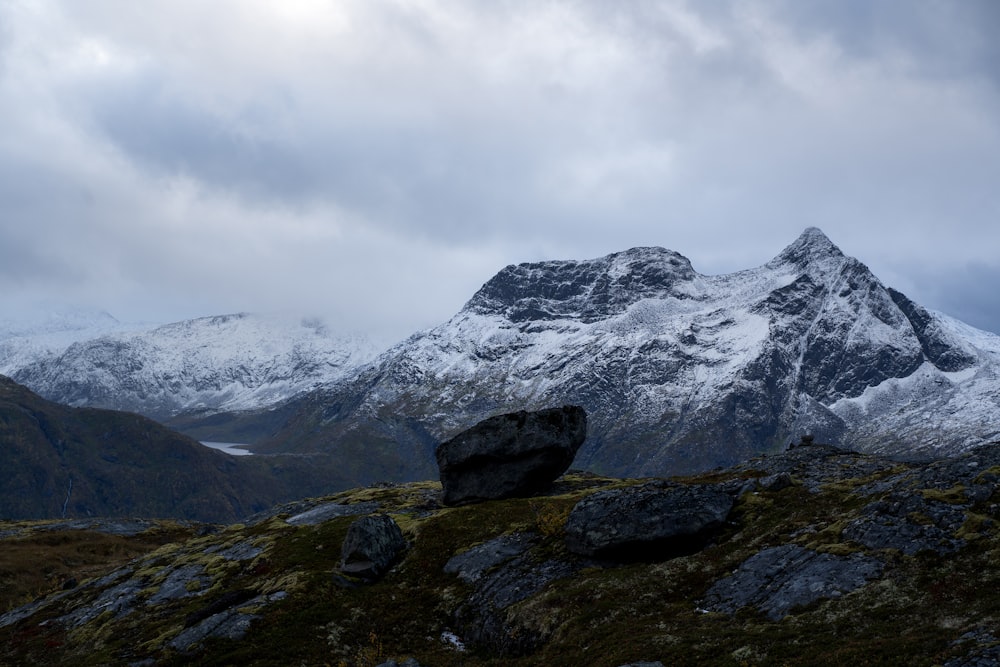 Una montaña cubierta de nieve con una roca en primer plano