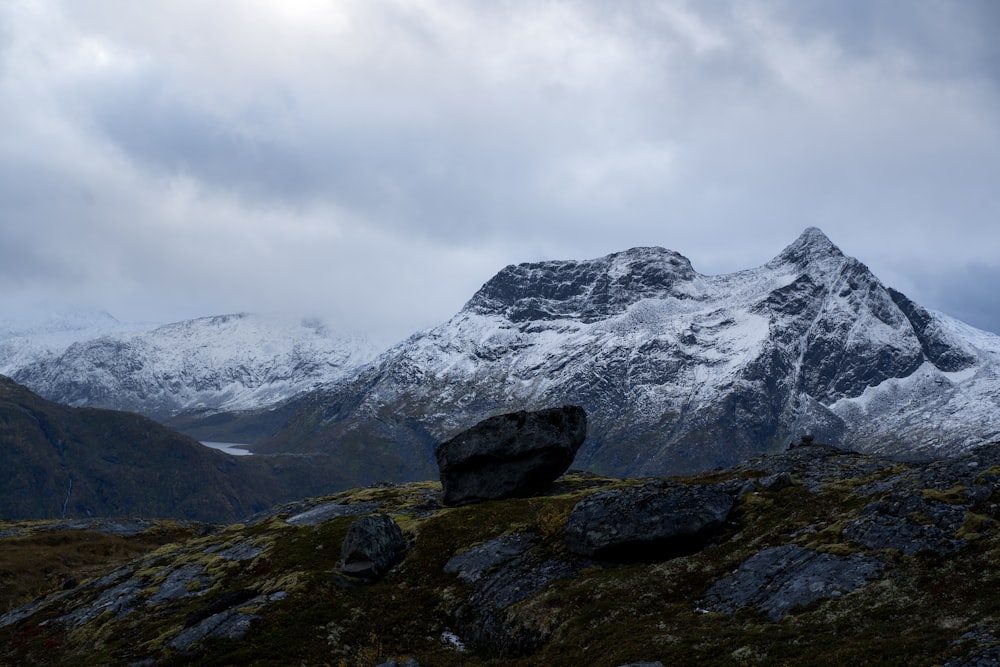 a snow covered mountain with a rock in the foreground