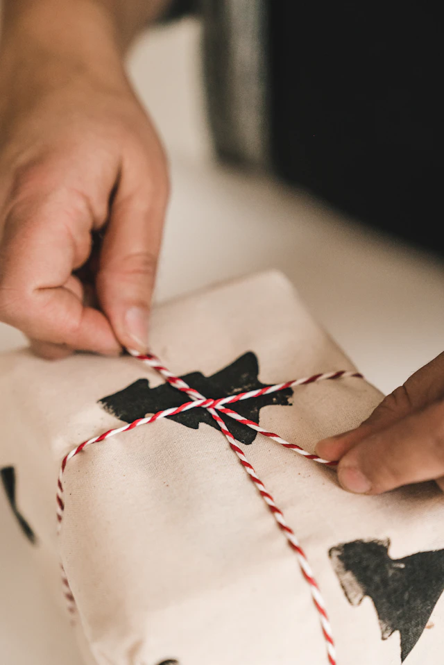 Mani che completano una confezione regalo con spago e sigillo