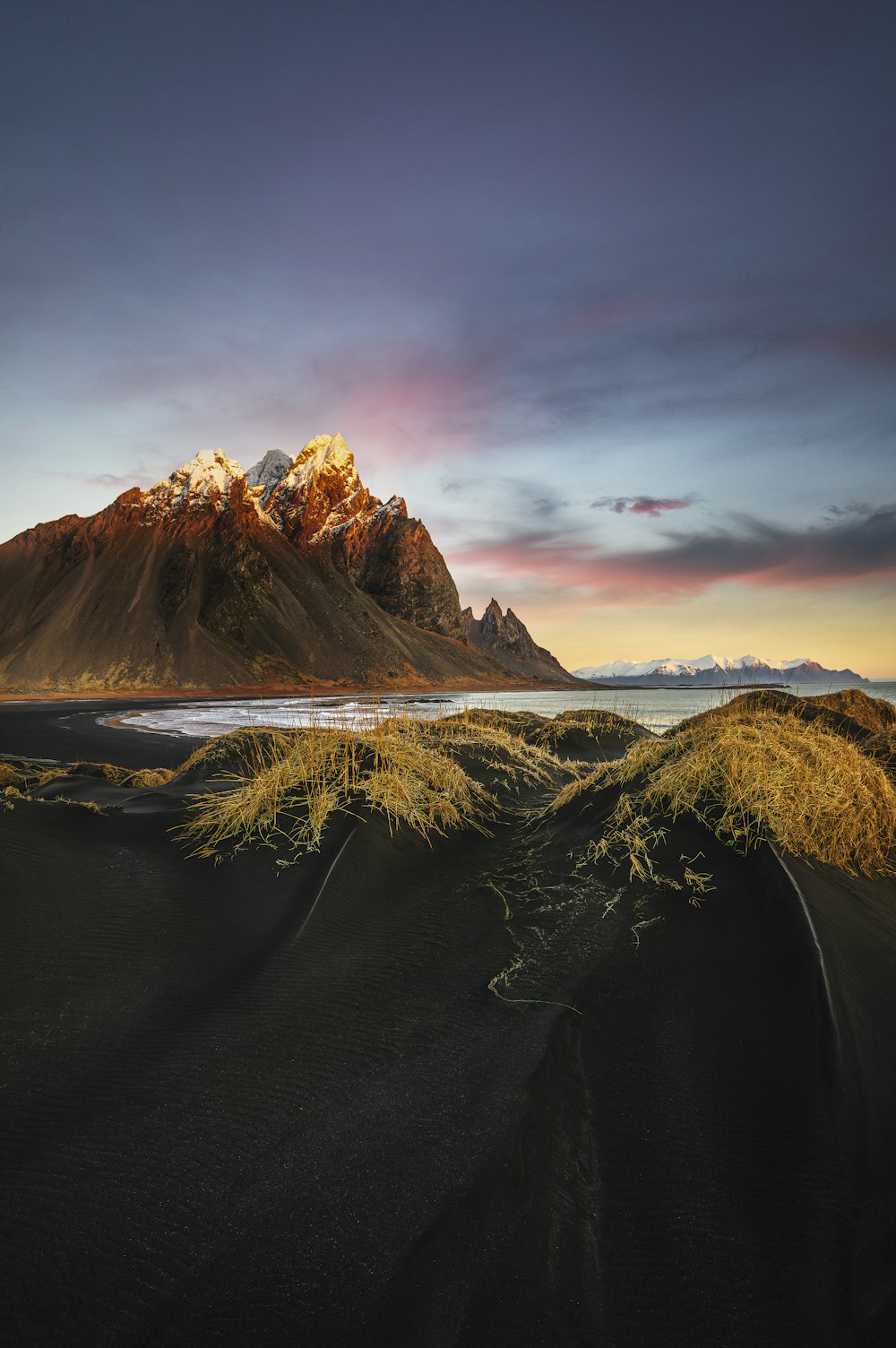 a mountain with snow on it and grass in the foreground