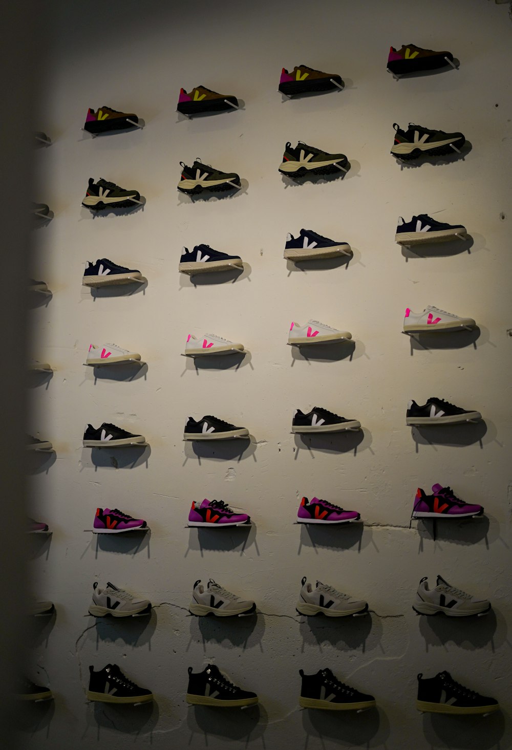 a wall with many pairs of shoes hanging on it