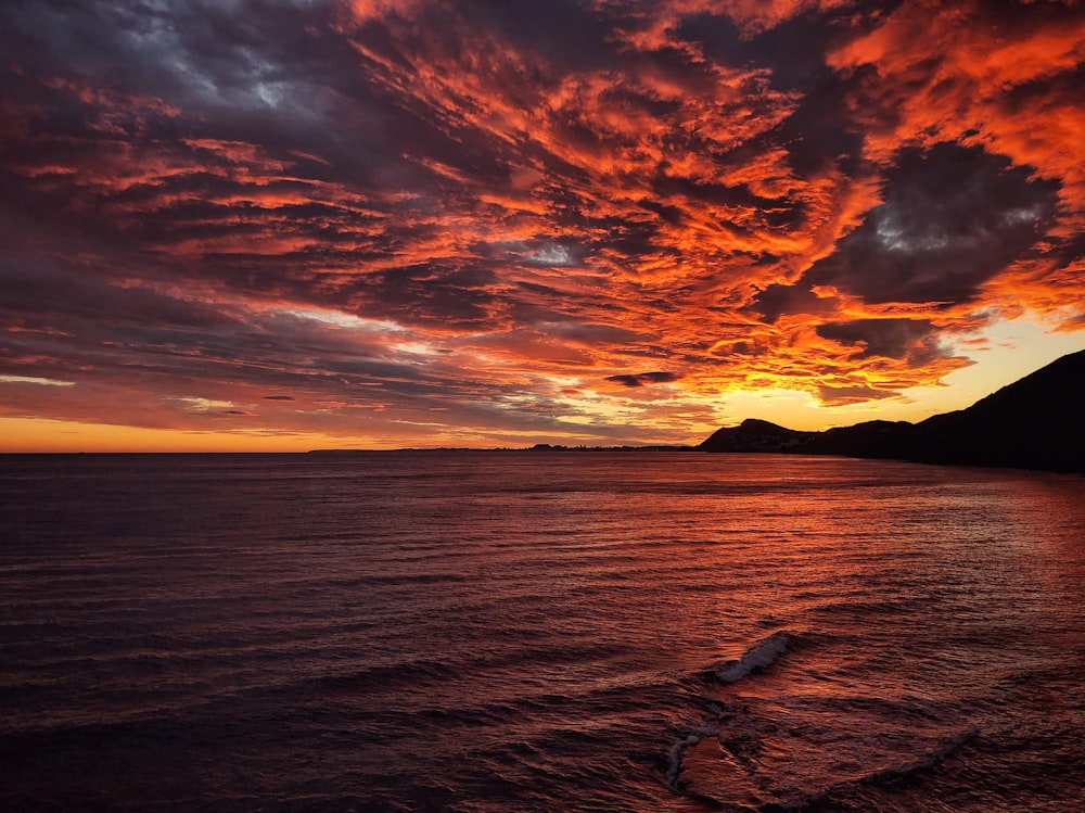 a sunset over a body of water with mountains in the background