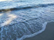 Soft ocean waves with white foam breaking gently on the shore at golden hour.