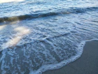 Soft ocean waves with white foam breaking gently on the shore at golden hour.
