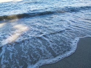 Gentle ocean waves rolling onto a sandy shore under soft sunlight.