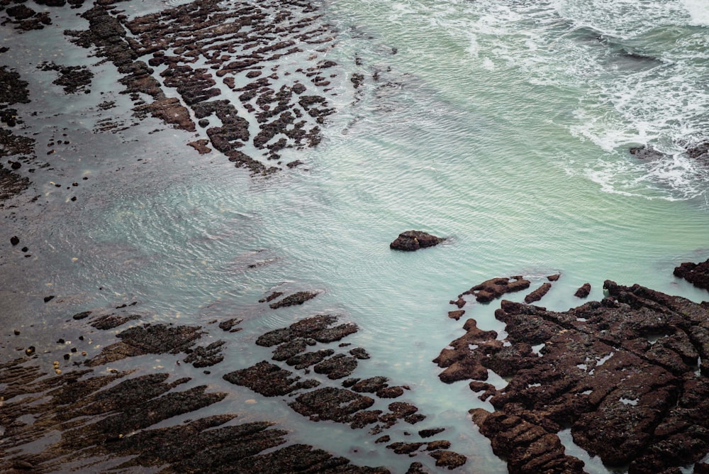 an aerial view of the ocean and rocks