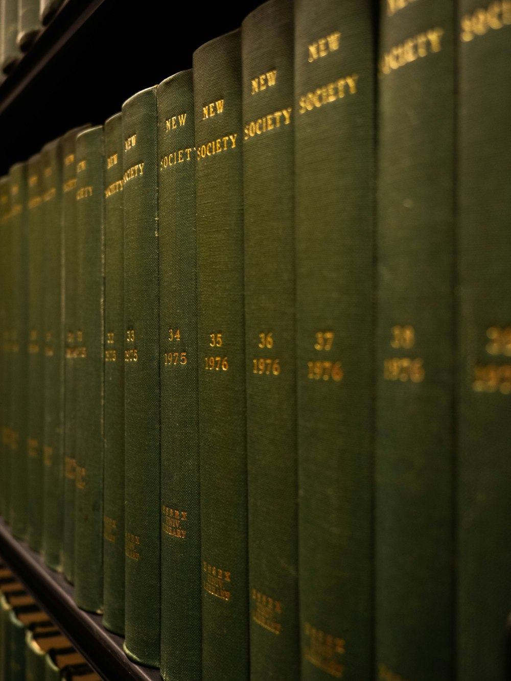 a row of green books sitting on top of a shelf