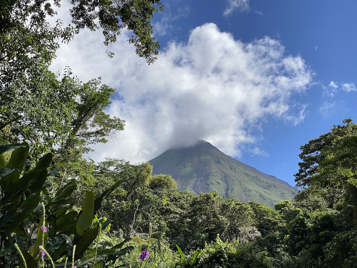Costa Rica March — Arenal Volcano rising through cloud above lush green forest in San Carlos