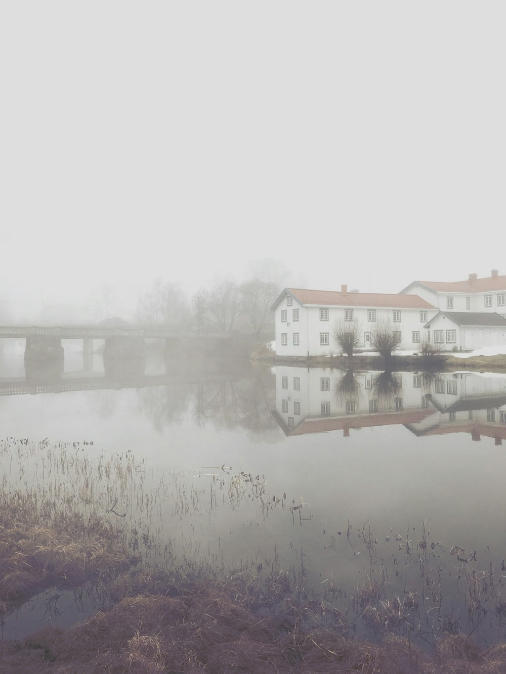 a body of water with a house and bridge in the background