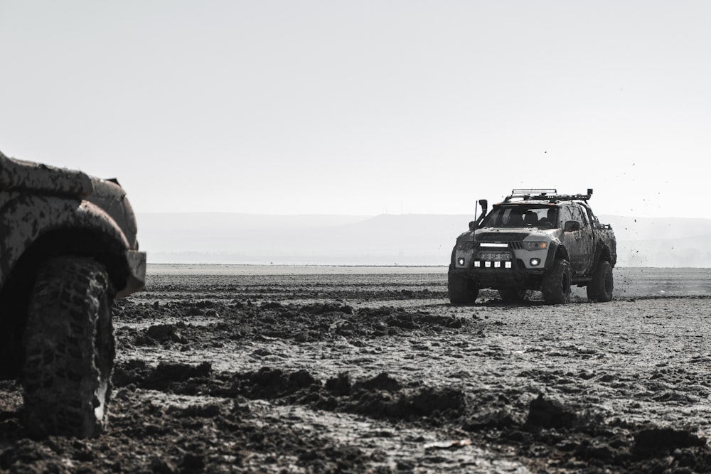 a jeep driving through a muddy field in the middle of the day