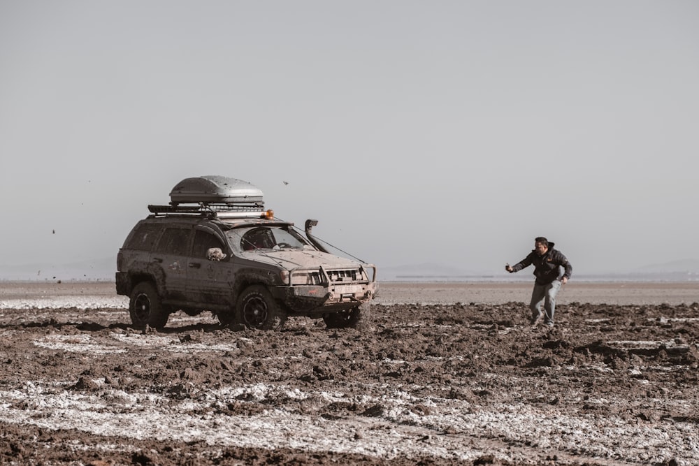 a man standing next to a vehicle in a muddy field