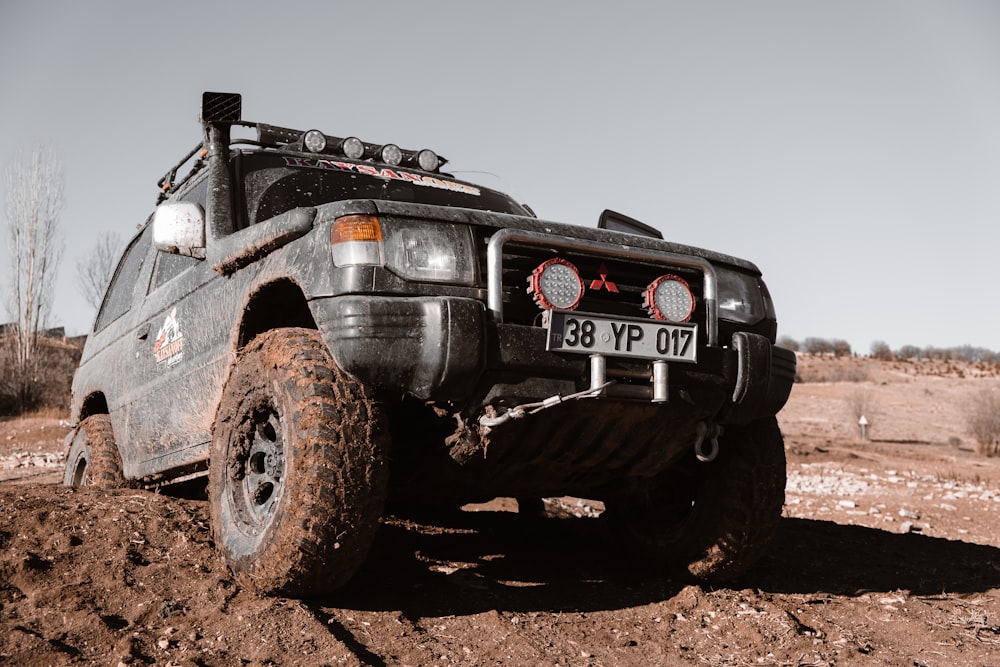 a black truck driving on a dirt road