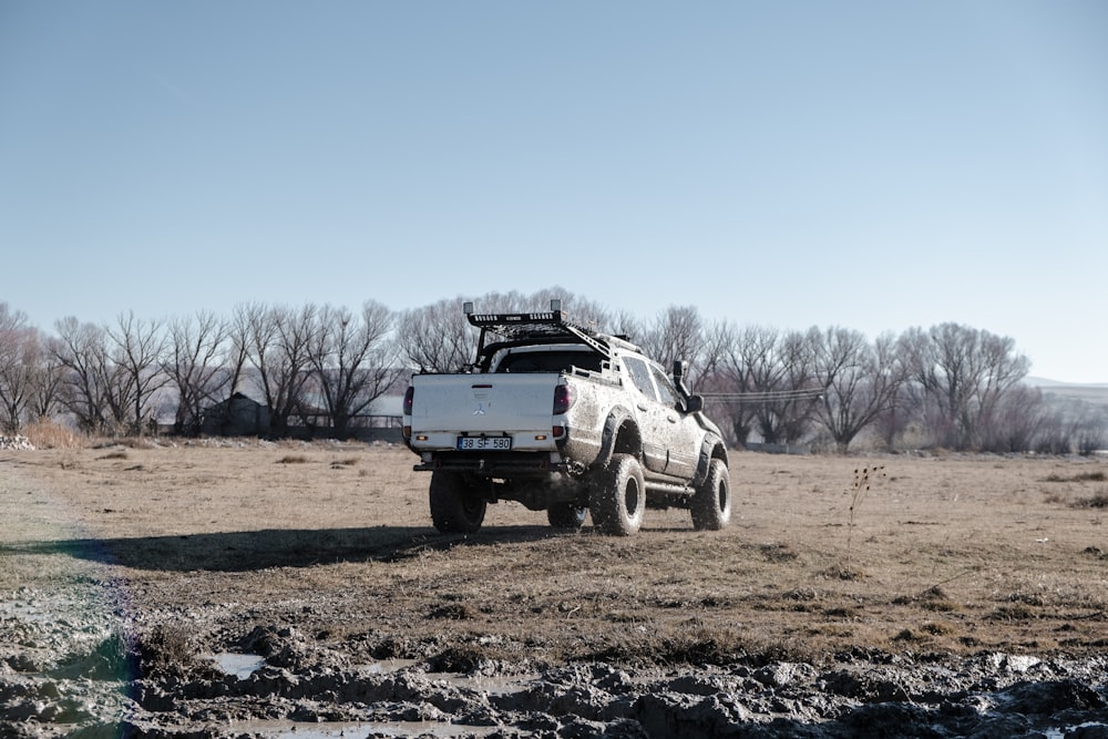 a white truck parked on top of a dirt field