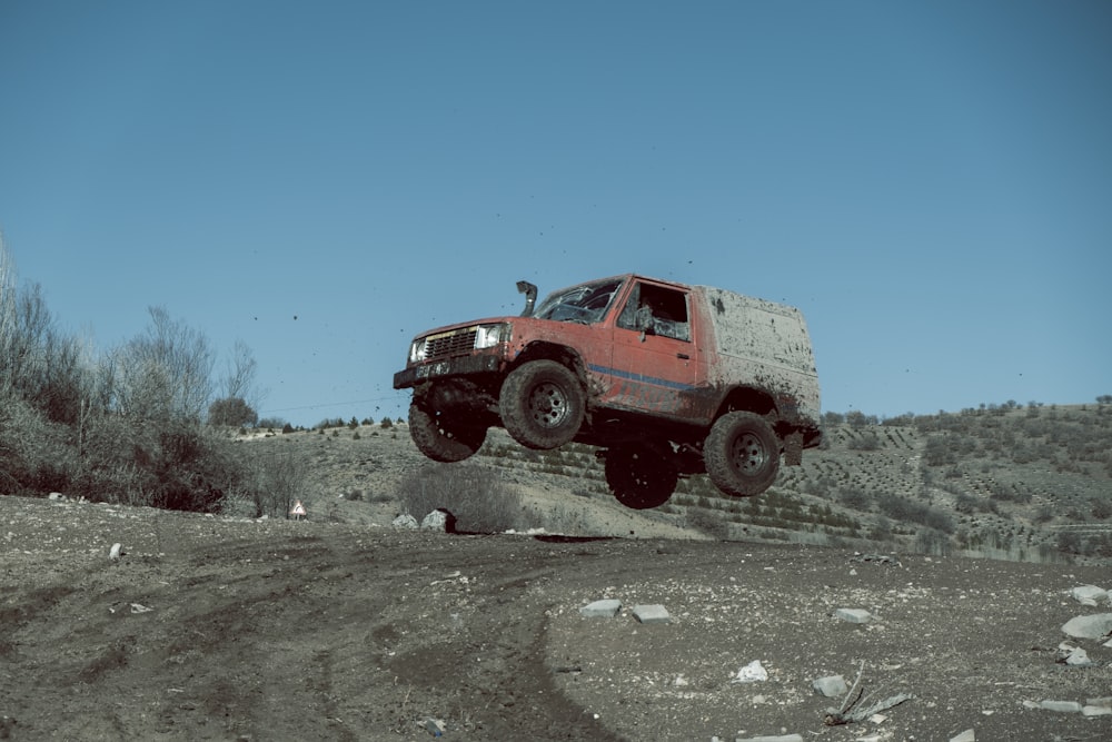 a red truck jumping over a pile of rocks
