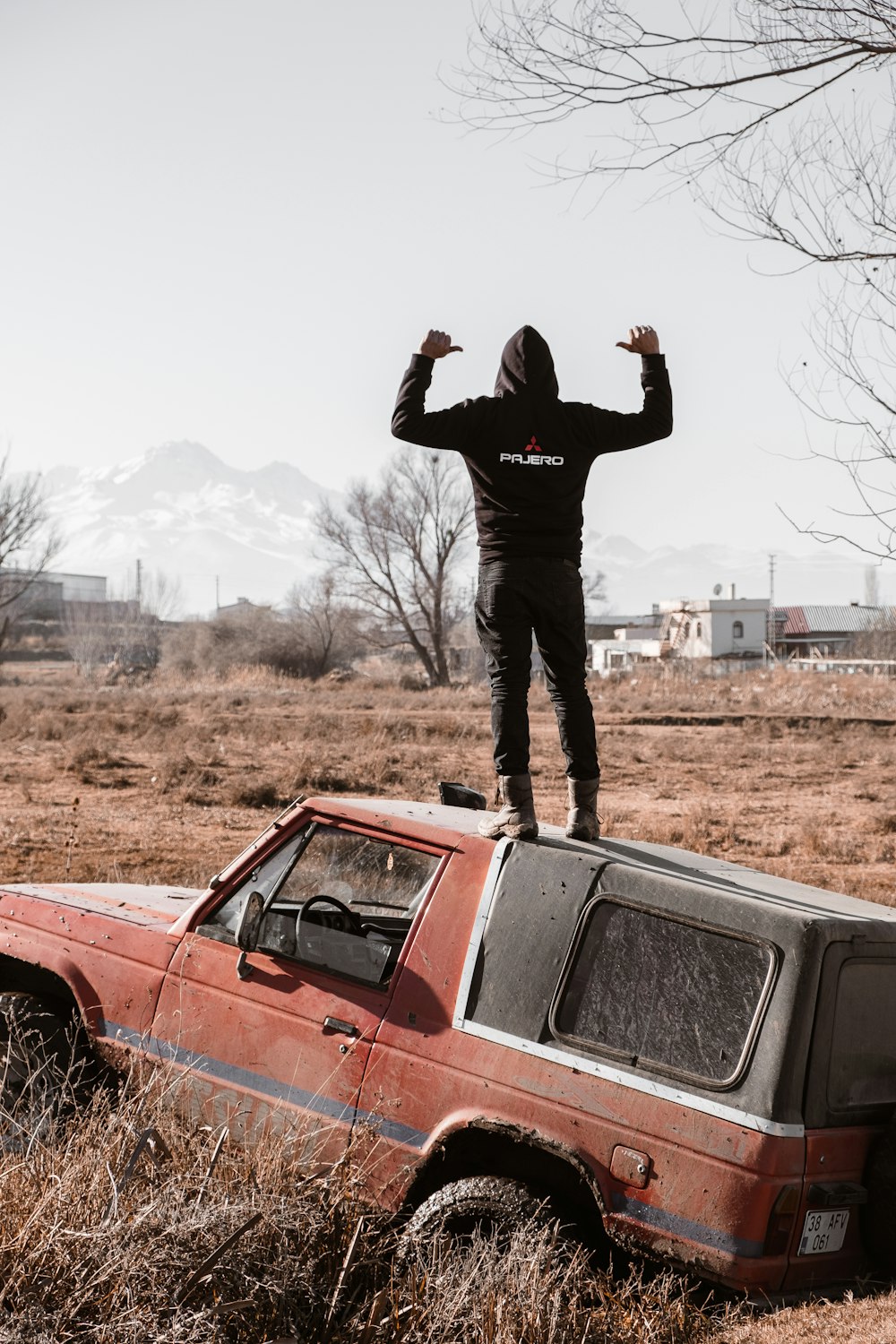 a man standing on top of a car in a field