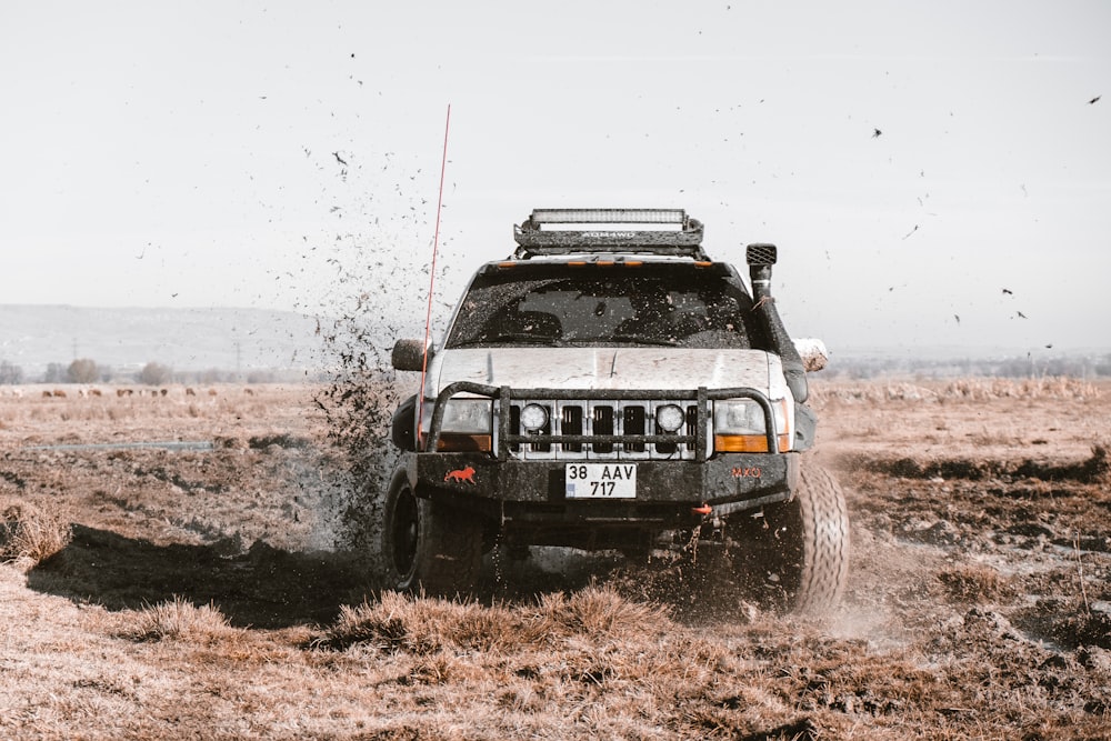 a white truck driving through a field covered in mud