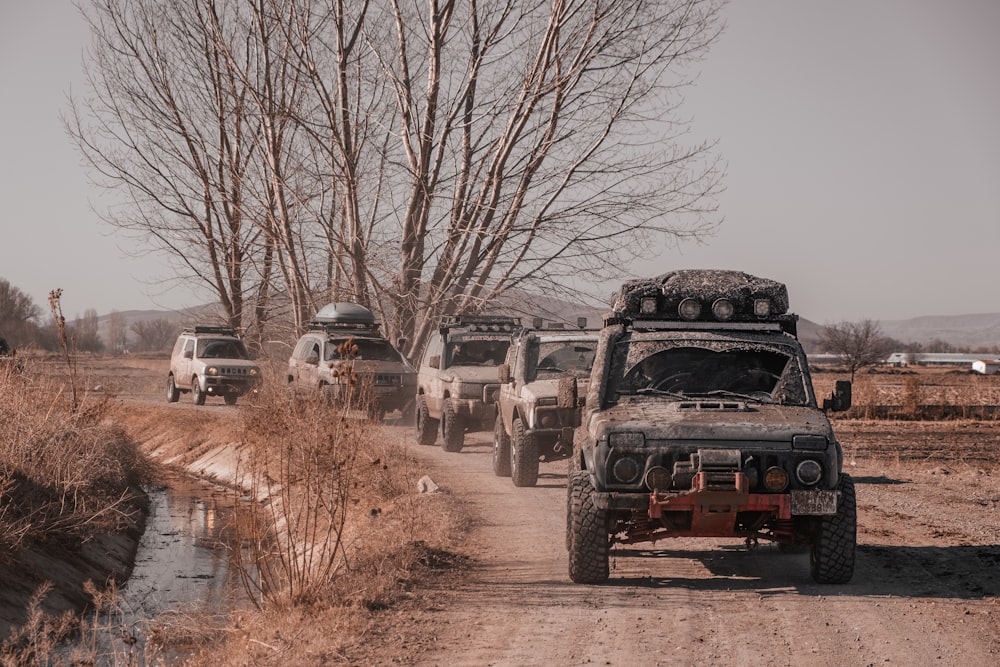 a group of jeeps driving down a dirt road