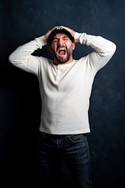 a man in a white shirt is holding his hands on his head