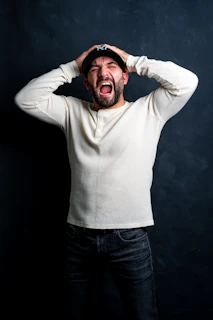 a man in a white shirt is holding his hands on his head