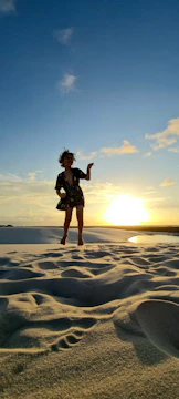 A child jumping joyfully on soft sand with sun-kissed backlight.